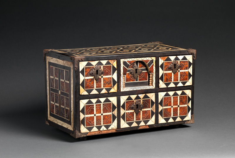Wooden casket with iron fittings and geometric ebony, tortoiseshell, and bone inlay, photographed on a neutral gray background.