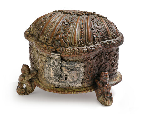 Ornate wooden box in the shape of a shell with detailed carvings, metal lock, and three small feet shaped like mythical creatures, photographed on a white background.